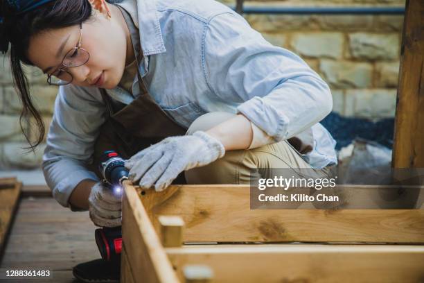 asian woman doing carpentry work in the yard - elektrisch gereedschap stockfoto's en -beelden