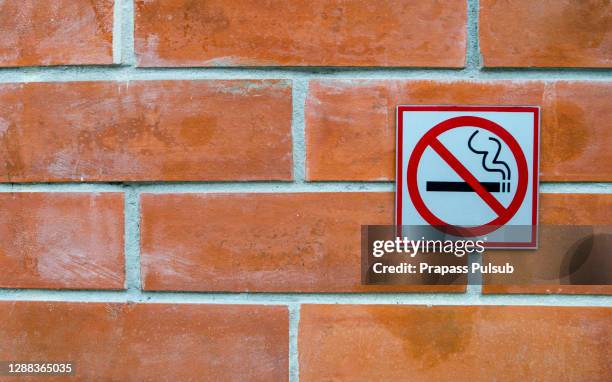 no smoking sign on orange brick wall - no smoking sign stock pictures, royalty-free photos & images