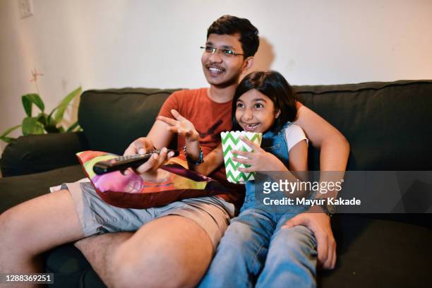 brother and sister watching tv sitting on sofa - indian sibling stock pictures, royalty-free photos & images