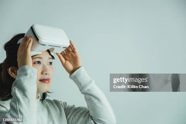 asian woman taking her vr headset off - entfernen stock-fotos und bilder