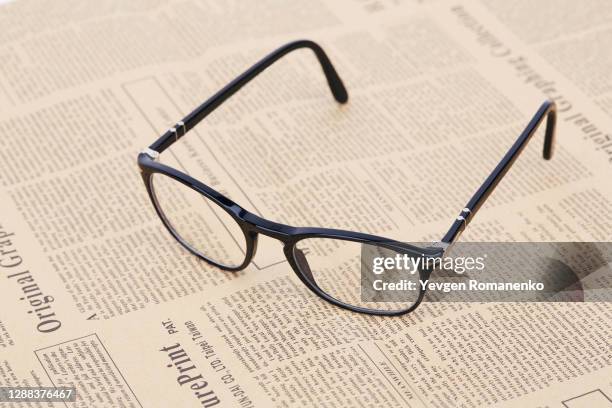 black reading glasses on a newspaper - article fotografías e imágenes de stock