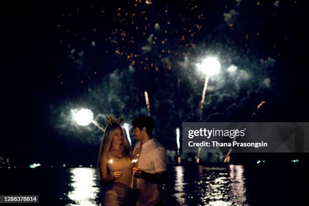 silhouette couple enjoying fireworks at seashore - emirati enjoy stock-fotos und bilder