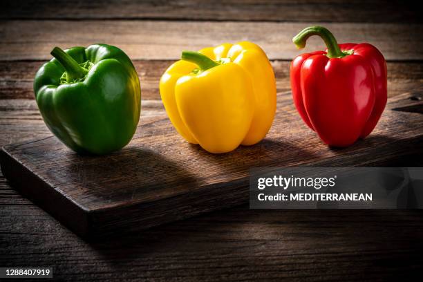 three colorful bell peppers red yellow and green colors in a row on wood - green bell pepper imagens e fotografias de stock