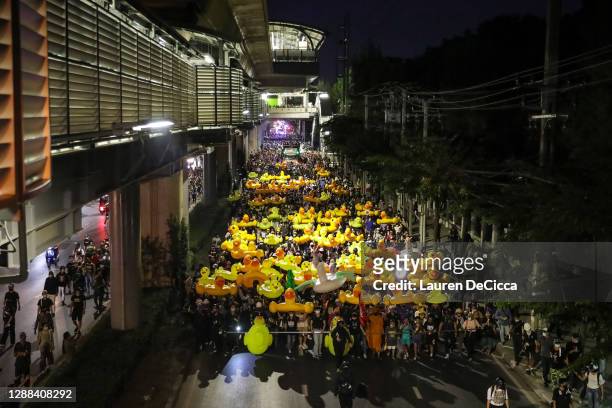 Protesters march while carrying inflatable yellow ducks outside the headquarters of the 11th Infantry Regiment on November 29, 2020 in Bangkok,...