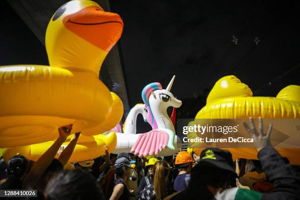 Protesters march while carrying inflatable yellow ducks outside the headquarters of the 11th Infantry Regiment on November 29, 2020 in Bangkok,...