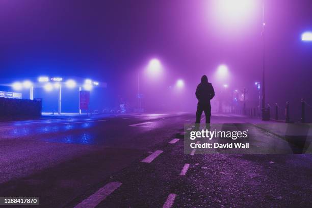 a hooded figure back to camera standing on a empty road in a city on a foggy, winters night. worcester, uk - spooky street stock pictures, royalty-free photos & images