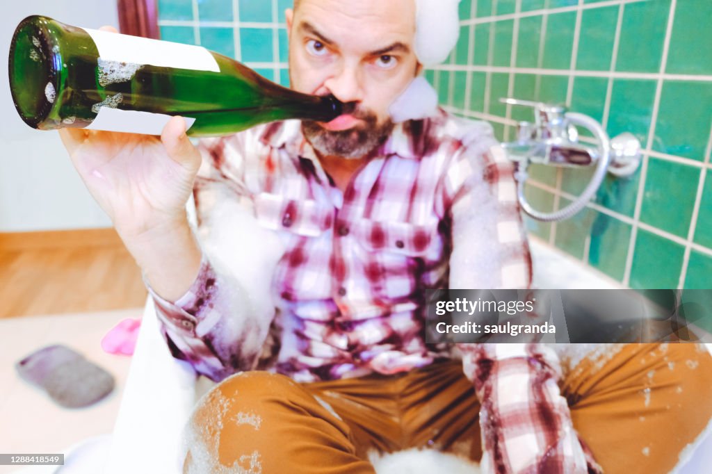 Drunk man drinking in the bathtub