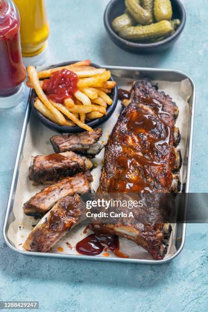 pork ribs in a baking tray with crisps and pickled - spare rib stock-fotos und bilder