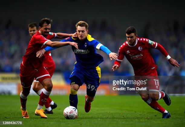 Joe Pigott of AFC Wimbledon battles for the ball with Tyler Frost and Jack Powell of Crawley Town during the FA Cup Second Round match between AFC...