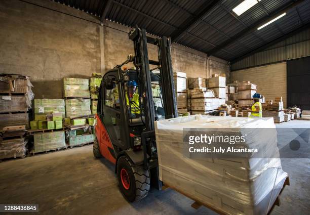 wide angle image of forklift lifting construction material with a woman working in the background.construction workers image - construction equipment stock pictures, royalty-free photos & images