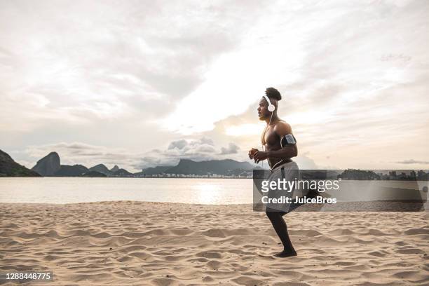 handsome brazilian shirtless man jogging at the beach - hunky guy on beach stock pictures, royalty-free photos & images