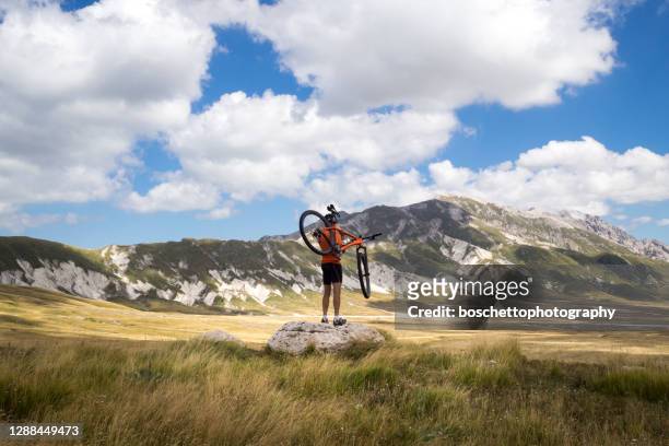 hombre llevando sobre los hombros su bicicleta de montaña, mirando hacia otro lado en un valle - abruzzi fotografías e imágenes de stock