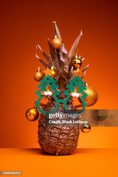 golden pineapple with christmas sunglasses on orange background. - glitter fruit stock pictures, royalty-free photos & images