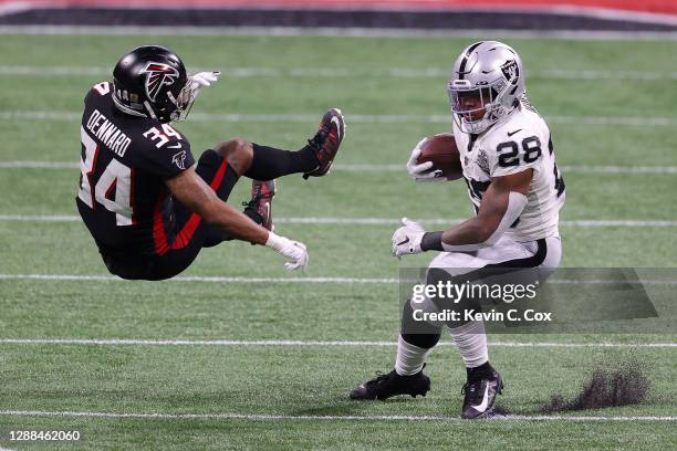 Josh Jacobs of the Las Vegas Raiders rushes with the ball against Darqueze Dennard of the Atlanta Falcons at Mercedes-Benz Stadium on November 29,...