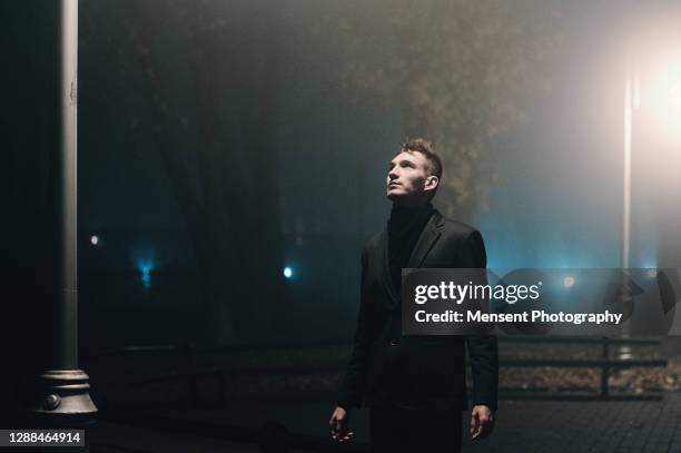 silhouette of a man standing in an empty street  in a foggy night - dark atmosphere stock pictures, royalty-free photos & images