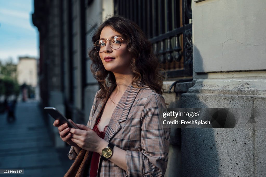 Een Mooie Vrouw die zich in de Straat bevindt, die haar Smartphone houdt