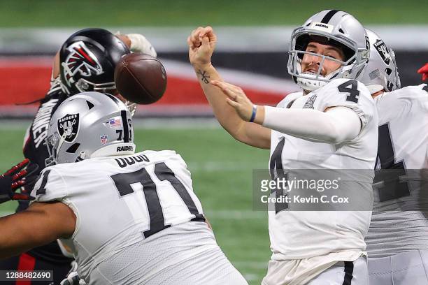 Derek Carr of the Las Vegas Raiders is stripped of the ball during their NFL game against the Atlanta Falcons at Mercedes-Benz Stadium on November...