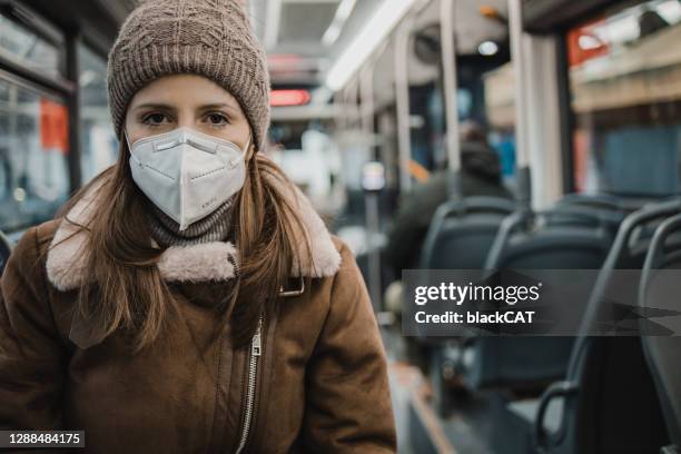 porträt einer frau mit gesichtsmaske in öffentlichen verkehrsmitteln - coronavirus winter stock-fotos und bilder