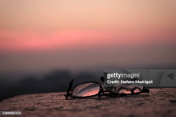 old glasses on the wall at sunset, reflected in the lenses - broken spectacles stock pictures, royalty-free photos & images