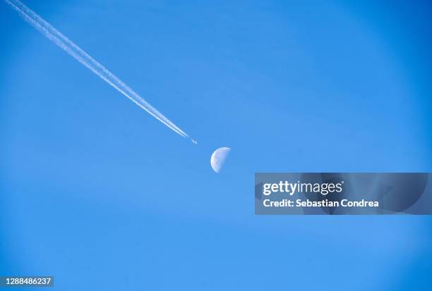 blue sky with moon, and plane passing through the moon during the day. - trainee photos et images de collection