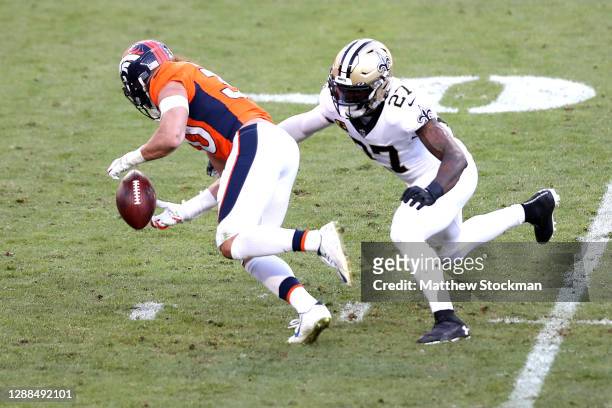 Phillip Lindsay of the Denver Broncos fumbles ahead of Malcolm Jenkins of the New Orleans Saints during the second quarter of a game at Empower Field...