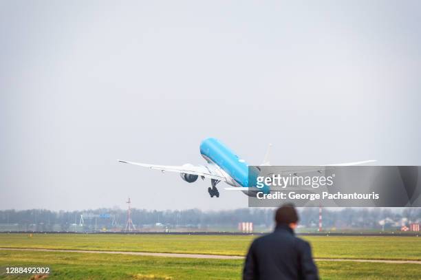 a blurres person looking at a large passenger plane taking off - george frost company stock-fotos und bilder