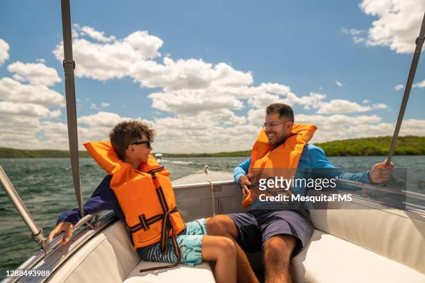 vater und sohn in rettungswesten genießen schnellbootfahrt - father son sailing stock-fotos und bilder
