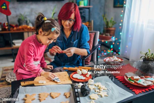 charming mother and daughter decorating gingerbread cookies with a chocolate chips - 2 5 months stock pictures, royalty-free photos & images