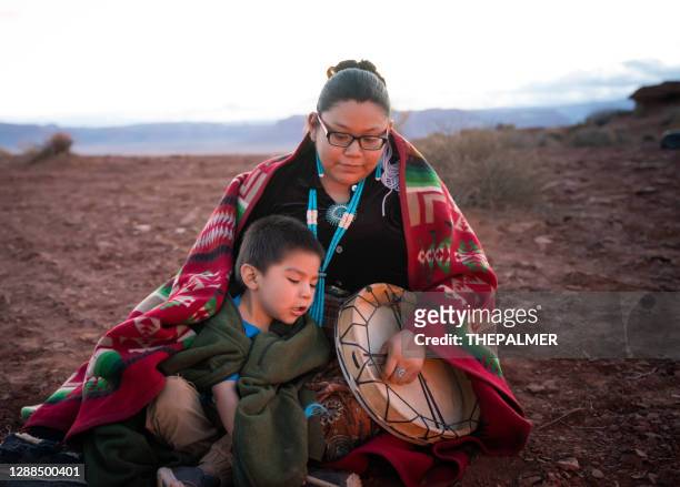 de jonge vrouw die van navajo een traditionele trommel met weinig broer rond kampvuur op de woestijn van arizona houdt - native american reservation stockfoto's en -beelden