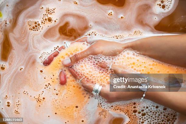 orange salt bath bomb dissolves in the hand. - jewellery background stock pictures, royalty-free photos & images