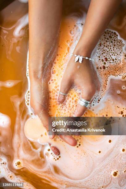 orange salt bath bomb dissolves in the hand. - bath bomb stock pictures, royalty-free photos & images