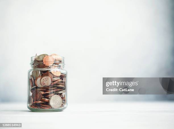 change jar filled with coins on gray background - us coin stock pictures, royalty-free photos & images