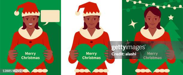 smiling beautiful teenage girl dressed in a santa claus suit holding a heart shape sign and looking at camera - ethnic woman at christmas stock illustrations