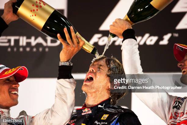 German Red Bull Racing Formula One driver Sebastian Vettel has champagne poured on him by McLaren driver Lewis Hamilton and his teammate Jenson...