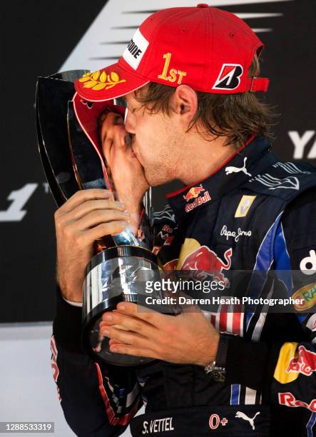 German Red Bull Racing Formula One driver Sebastian Vettel on the winners podium kissing the winners trophy in celebration of winning both the race...