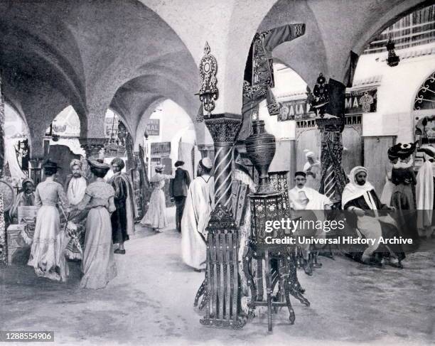 Exposition Universelle Paris, 1900; an interior of a Tunisian market place selling carpets, silk, sweet meats and perfumes, among other things..