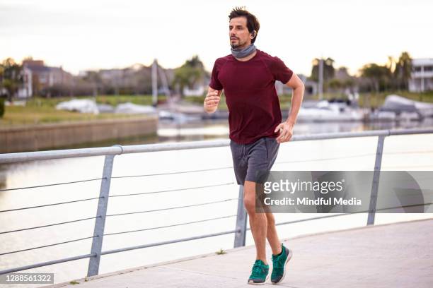 homme faisant du jogging sur la promenade - buff photos et images de collection