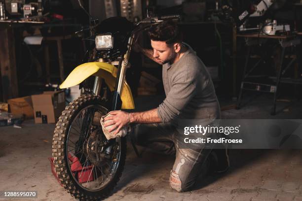 junger mann repariert motocross-bike in werkstatt - the moto x film experience stock-fotos und bilder