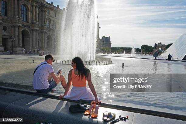 Touristes au bord de la fontaine de la Pyramide du Louvre, 2 juin 2019, Paris 1er arrondissement, France.