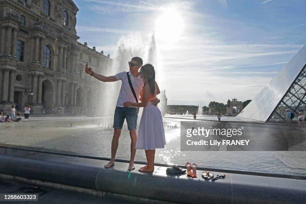 Touristes faisant un selfie au bord de la fontaine de la Pyramide du Louvre, 2 juin 2019, Paris 1er arrondissement, France.