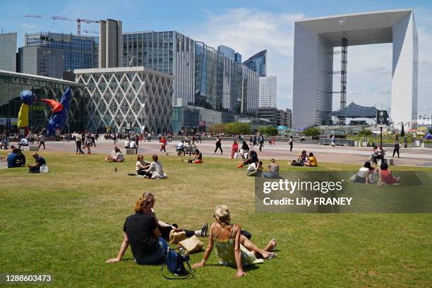 Groupe de personnes sur la pelouse de l'esplanade durant la pause déjeuner, la Grande Arche, à La Défense, 10 juillet 2019, Paris, France.