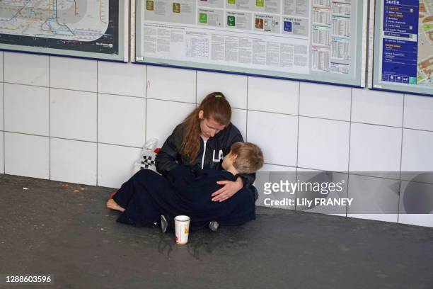 Femme SDF, avec son enfant dans les bras, mendiant dans le métro à la station de La Défense, 10 juillet 2019, Paris, France.
