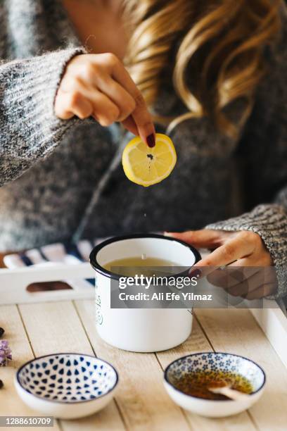 a female model is drinking herbal tea for flu, she is pouring herbal tea into a white enamel cup - herbal tea stock pictures, royalty-free photos & images
