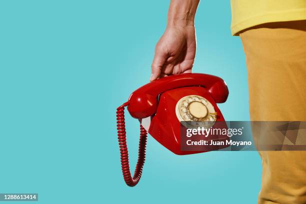 man with an old red telephone in his hand - antique phone photos et images de collection