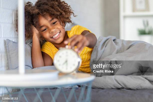 young girl waking up with alarm clock - good night imagens e fotografias de stock