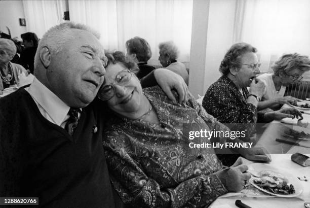 Couple de retraités à table se faisant un calin Ehpad, maison de retraite à Vitry-sur-Seine, Val-de-Marne, France.