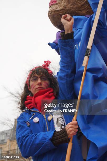 Femme levant le poing, association ATTAC, les "Grandes gagnantes, habillée d'un bleu de travail, de gants jaunes, en référence à Rosie la riveteuse,...