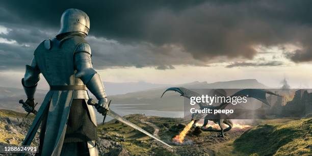 cavaliere guarda dall'alto in basso su enorme drago che respira fuoco vicino al castello - dragon foto e immagini stock