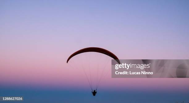 paraglider flying in the late afternoon - purple sunset stock pictures, royalty-free photos & images