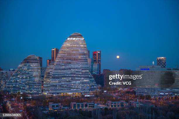 The moon is seen above Wangjing SOHO during a penumbral lunar eclipse on November 30, 2020 in Beijing, China.